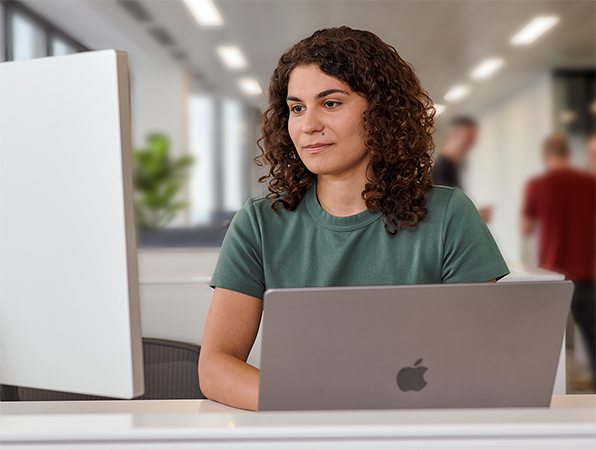 Et Apple-teammedlem bruger en MacBook og et Studio Display på et kontor.