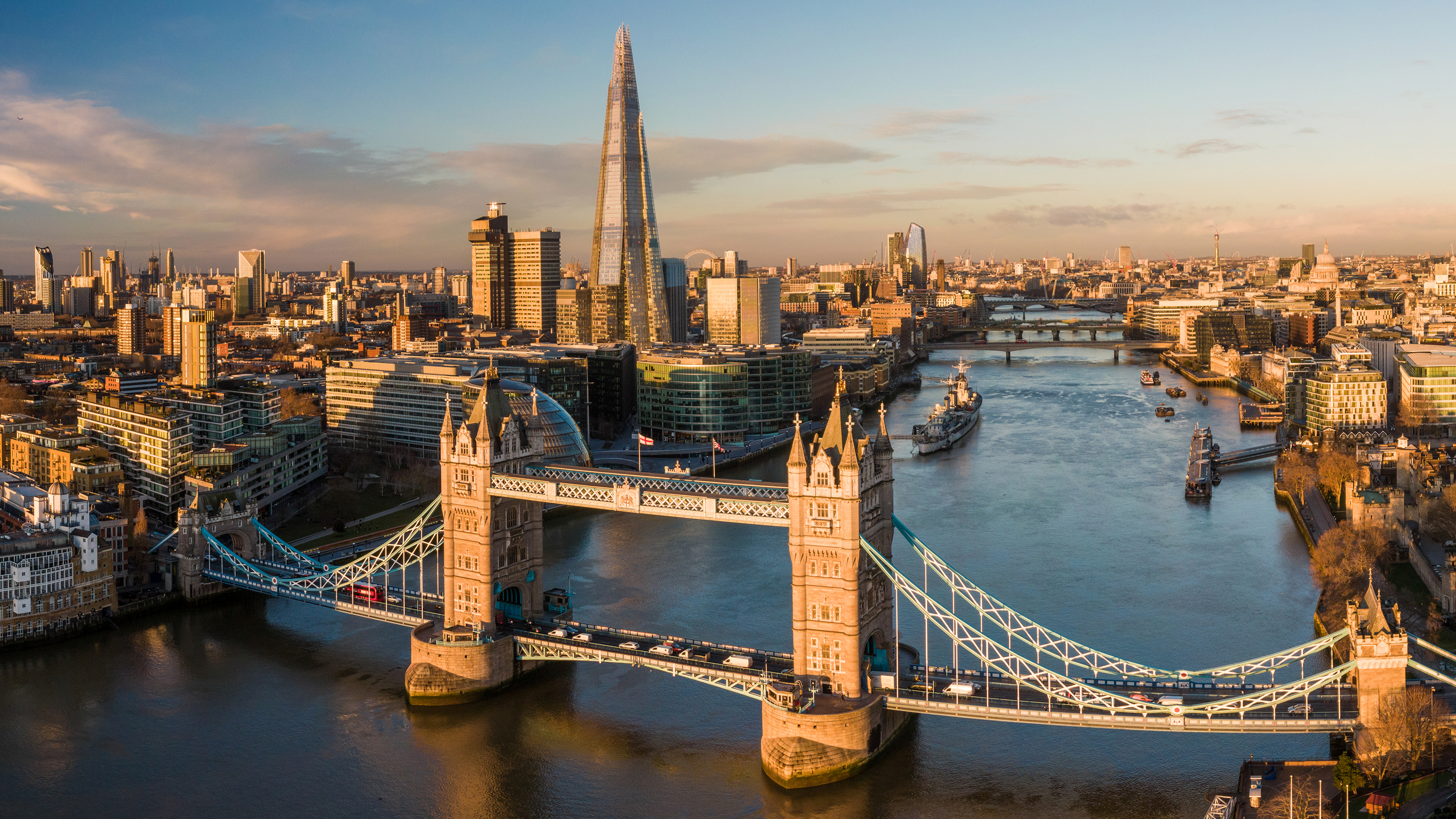 Luftfoto af London og floden Themsen med Tower Bridge i forgrunden.