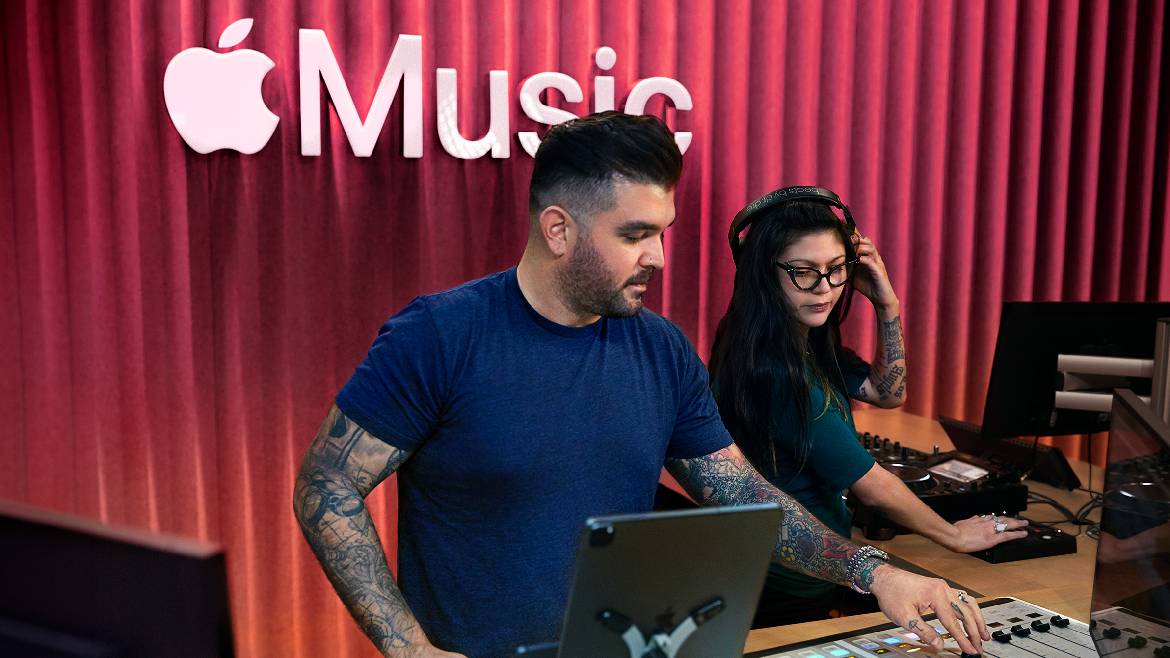 Two Apple colleagues using a sound-mixing board in an Apple Music studio.