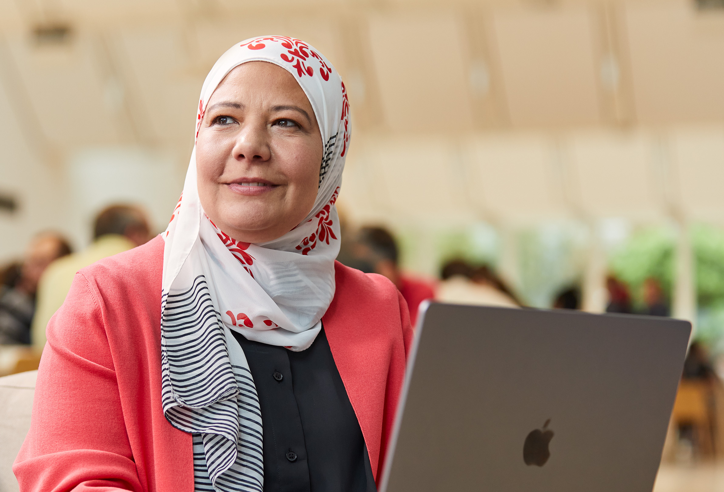 En Apple-medarbejder, der kigger til venstre, sidder og arbejder på en MacBook.