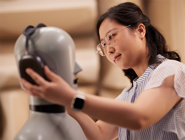 En medarbejder fra Apple Hardware-teamet sætter Apple AirPods Max-hovedtelefoner på en mannequin i et laboratorie.