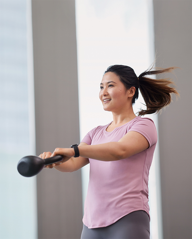 En Apple-medarbejder midt i en bevægelse, mens hun træner med en kettlebell.