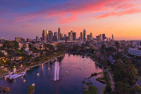 Vista aérea dos arranha-céus de Los Angeles com um parque e um lago em primeiro plano.