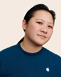 Apple Retail employee with long hair, smiling at the camera.