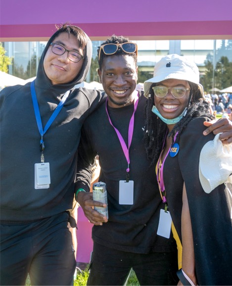 Three Apple interns standing with their arms around each other, smiling into the camera.