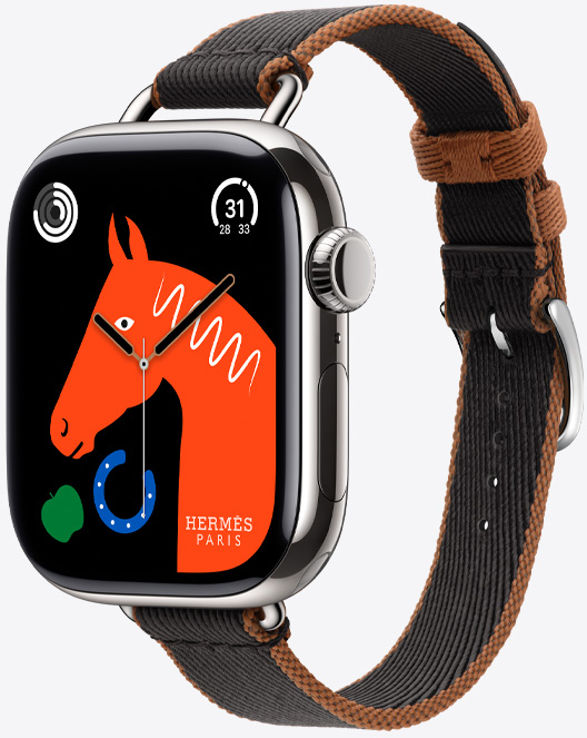 Angled view of the new Twill Jump Attelage Single Tour strap in Noir/Gold (black with gold trim) with the ‘Lucky Horse’ watch face featuring an orange horse’s head, a green apple and a blue horseshoe.