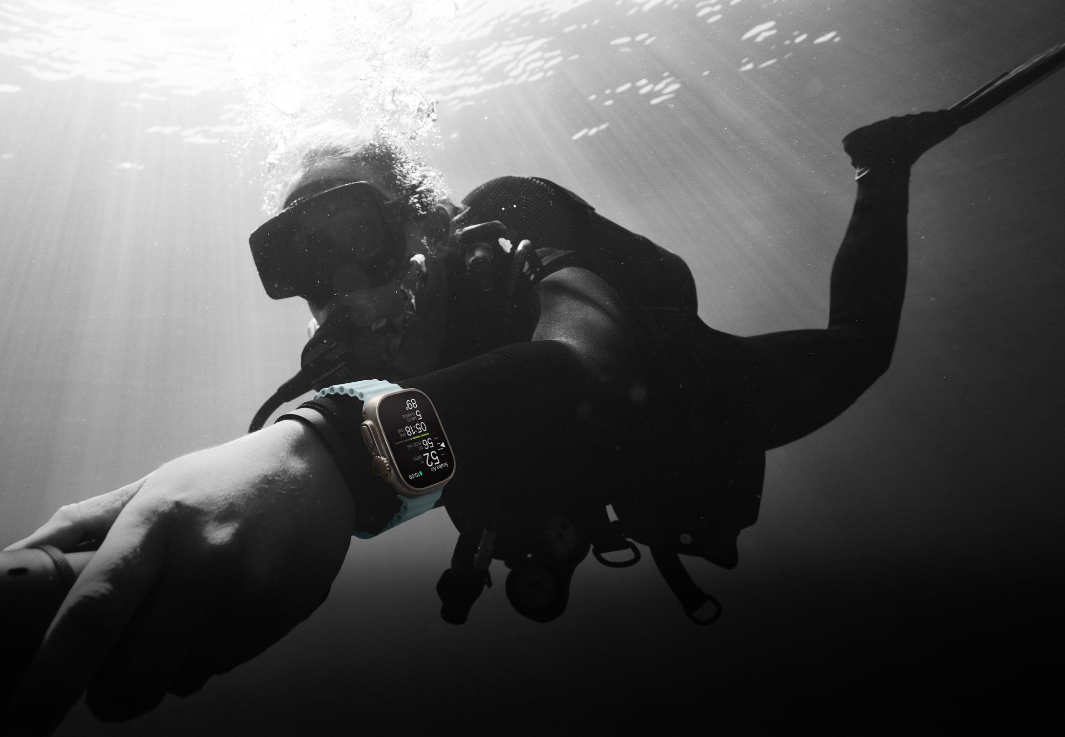 Seorang penyelam scuba mengenakan Apple Watch Ultra 2 di bawah permukaan air.